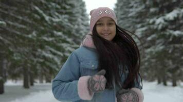 glücklich Mädchen läuft durch das Winter Wald im ein gut Stimmung und lächelt. schleppend Bewegung video