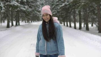 un hermosa niña camina mediante un invierno bosque con bueno alimento y giros alrededor sí misma. lento movimiento video