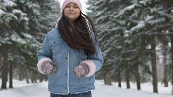 ung skön flicka kör genom de vinter- skog och ler medan har en Bra humör. långsam rörelse video