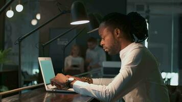 Creative business team, multiethnic group, coworking space. Creative african american man working in modern office using laptop video