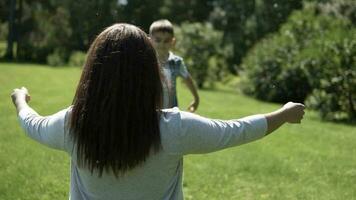 A small handsome son runs quickly to his mother in the arms and hugs her. slow motion. video