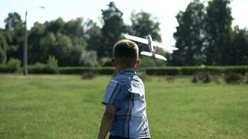 Little Boy is launching a toy plane in the park in sunny weather having a good mood. slow motion. HD video