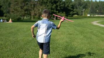 wenig Junge - - Pilot startet ein Spielzeug Flugzeug im das Park. schleppend Bewegung. video