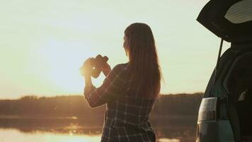 Finding strategy, Explore area, Find solution, Woman tourist. Woman tourist looking through binoculars while standing by the water next to the car during dawn video