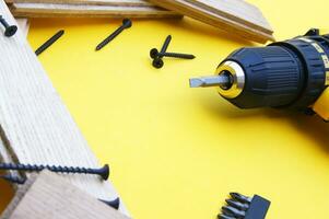 Yellow-black screwdriver on a yellow background, screws, a set of bits. photo