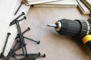 The yellow-black screwdriver on wood background, screws. photo