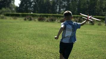 Little Boy is launching a toy plane in the park in sunny weather having a good mood. slow motion. video