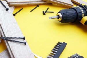 Yellow-black screwdriver on a yellow background, screws, a set of bits. photo