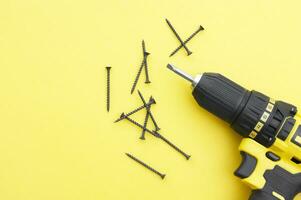 The yellow-black screwdriver on a yellow background, screws. photo