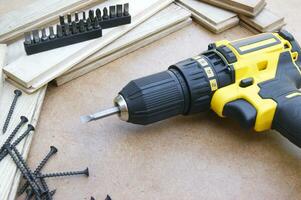 The yellow-black screwdriver on wood background, screws. photo