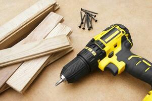 The yellow-black screwdriver on wood background, screws. photo