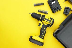 The yellow-black screwdriver on a yellow background, a set of bits. photo