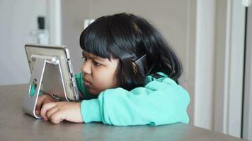 criança menina usando digital tábua sentado em uma mesa video