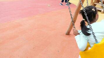 child having fun on a swing on the playground in public park. video