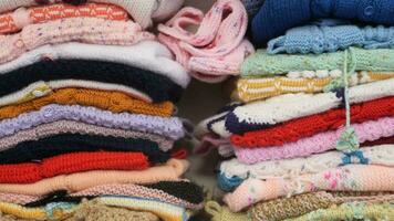 stack of knitted warm sweaters with different knitting patterns. video