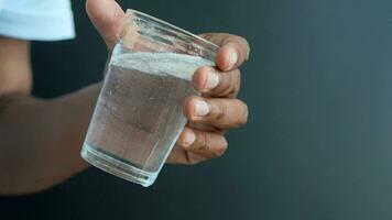 sosteniendo un vaso de agua sucia contra el fondo negro video