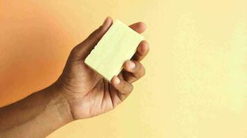 holding a natural soap bar against orange color background video