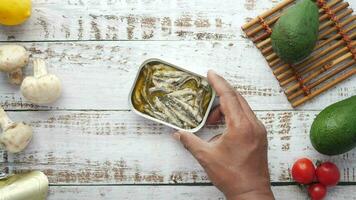 hand putting open tin of sardines on table video