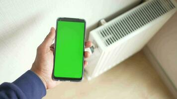 hand shows smartphone with mock up in screen with electric heater in background . video