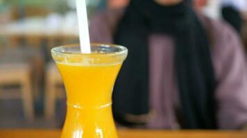 Dames Holding een glas van oranje sap zittend Aan cafe video