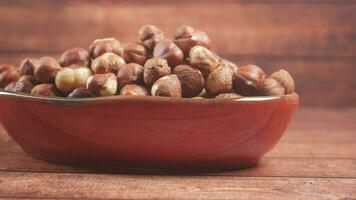 hazelnuts in a container on black background, video