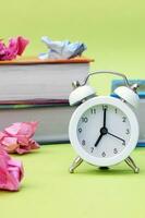 A white vintage clock in the foreground at 700 am on a light green background. photo