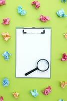 Magnifying glass, clipboard and crumpled colorful stickers around. photo