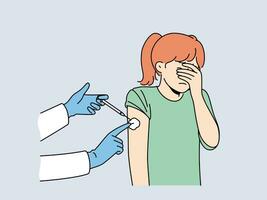 Crying little girl is afraid of injections and closes eyes during injection in shoulder and vaccination against measles or flu. Hands of doctor with syringe making injection to child vector