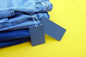 Detail of blue jeans, blank grey labels on yellow background. photo