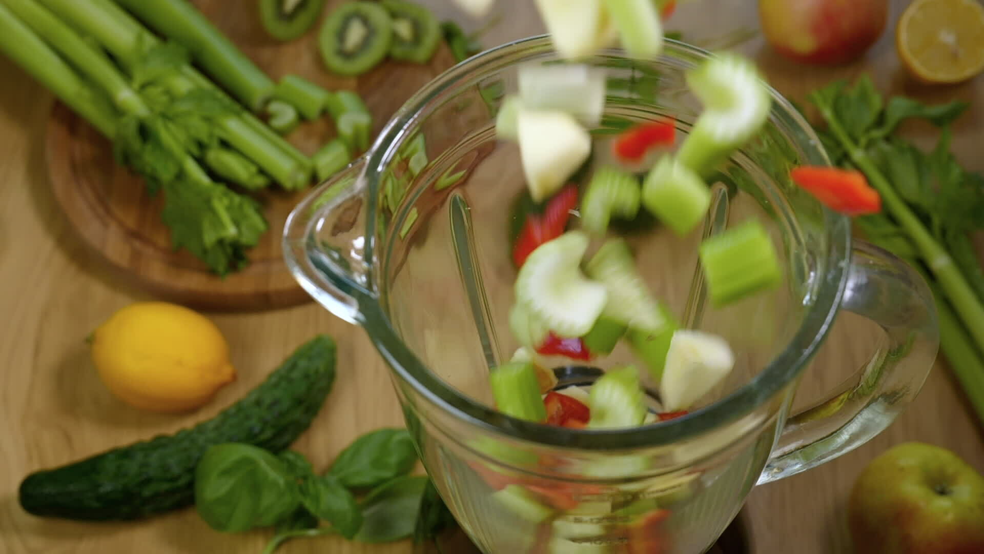 Vegetables fall in blender, super slow motion. Green smoothie in