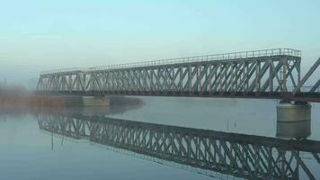 Aerial view of the railway bridge over the river in the fog in the early morning video