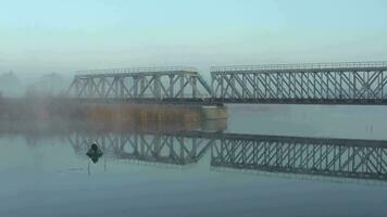 Railway bridge over a river in the fog in the countryside early in the morning video