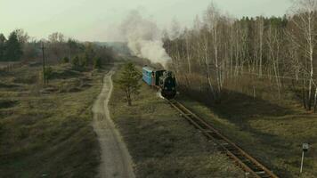 aéreo ver de antiguo vapor tren corriendo en el pistas en el campo. patrimonio histórico vapor locomotora con blanco fumar visto desde encima por zumbido. otoño. video