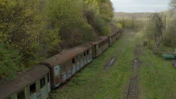 Aerial view of a retro train on the railway tracks. Drone flight over the old rusty wagons of the narrow gauge railway video