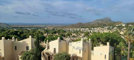 Panoramic view of a Mediterranean landscape with residential buildings and a mountain in the background under a clear sky. photo