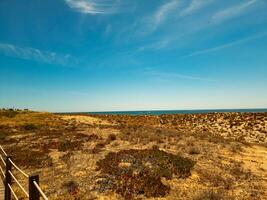 Wooden boardwalk by the beach with a clear blue sky. photo