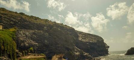 Scenic coastal landscape with rugged cliffs and waves crashing against the shore under a hazy sky. photo