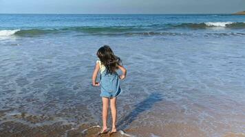 förtjusande liten flicka i solklänning, löpning barfota ensam på de tömma sandig tropisk strand på en skön värma solig dag. Lycklig barn njuter ett aktiva helgen utomhus. sport rekreation. barndom video