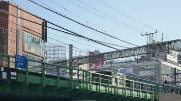 view to the japan railway trackway with train commuter moving passing and background of advertising neon billboard on the building in daytime video