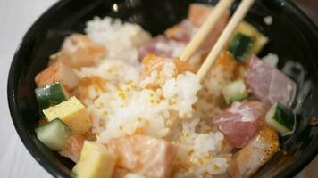 utilizando palillos a comer bara shirashi don, Fresco crudo Mariscos sashimi en arroz en japonés estilo video