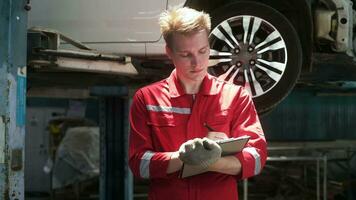 joven caucásico reparador analizando y fijación roto coche en coche reparar mecánico tienda video