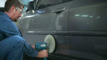 Caucasian man is using car polishing machine in repair mechanic painting shop video