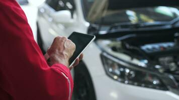 Close-up technician man hand using tablet analyzing car problems in auto repair shop . concept of auto repair and maintenance service. video