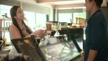 Young Asian service minded barista  with customer in coffee shop video