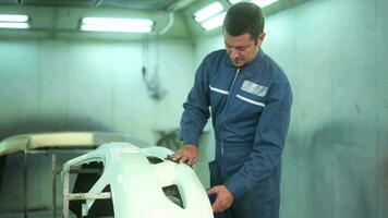 Caucasian man is cleaning car parts before spraying color in repair mechanic painting shop video