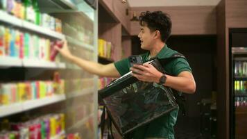 un asiático hombre entrega elegir bienes desde en línea orden en supermercado , en línea entrega Servicio concepto video