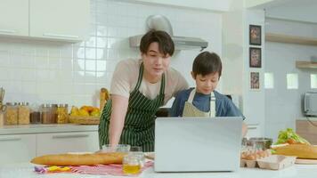glücklich lächelnd jung asiatisch Vater und Sohn Herstellung Video Anruf zu Mutter. genießen Kochen im Küche beim Zuhause