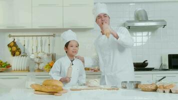 jovem ásia pai e dele filho vestindo chefe de cozinha uniforme cozimento juntos dentro cozinha às casa video