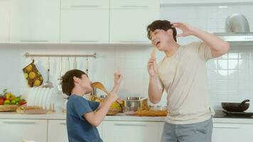 Happy Young Asian father and son cooking in kitchen at home video