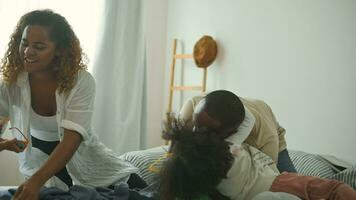 Happy African American Parents with  little daughters playing on the bed in bedroom at home, happy family concept video